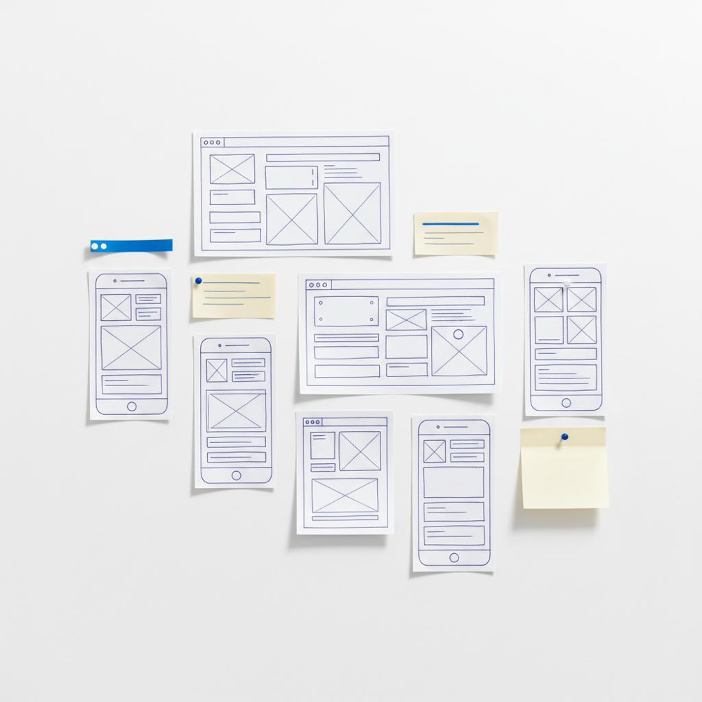 Flat-lay of wireframe thumbnails and sticky notes on a white background with #1a5bfb accent markers, minimalist layout for best website builder for professionals